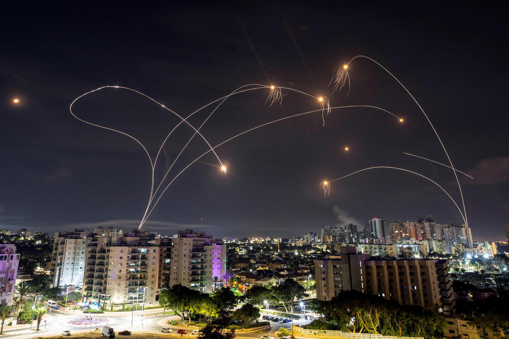 Night sky interception with defense missiles illuminating above a city skyline.